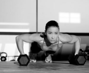 Gym woman push-up strength pushup with dumbbell